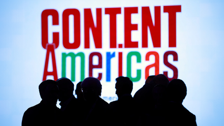 Photo image of a silhouetted group of people in front of a bright screen with the words Content Americas on it.