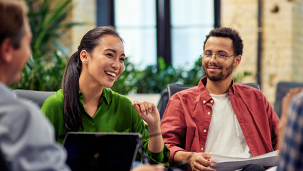 Photo of a diverse group of colleagues who are talking and smiling at each other.