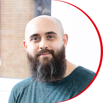 Headshot: Adam Turner, a man with a short brown beard and shaven head.