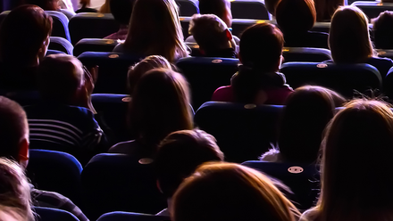 Photo of the backs of an audience watching a cinema screen, which is out of frame.