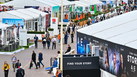 Photo taken from above of an outdoor walkway, lots of people are waking their way along it and there are branding boards lining either side.