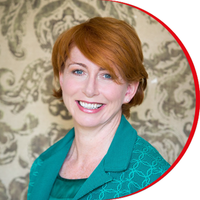 Headshot: Jane Kelly, a woman with short red hair and blue eyes, wearing a blue/green jacket and top.