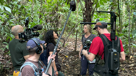 Photo of a small production crew shooting an interview with a contributor in a jungle.