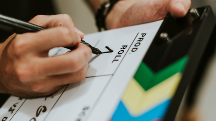 Photo of a hand writing the number '1' on a clapper board.