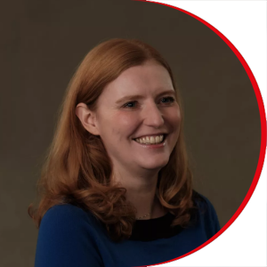 Headshot: Laura Crowley - a woman with long red hair wearing a royal blue top.