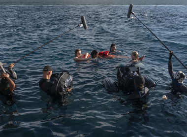 Production image from Dan Films: four young women are floating in the sea, a production crew dressed in wetsuits are filming them.