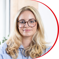 Headshot: Susie Heron Halliday, a young woman with long blonde hair and glasses, wearing a light blue shirt.