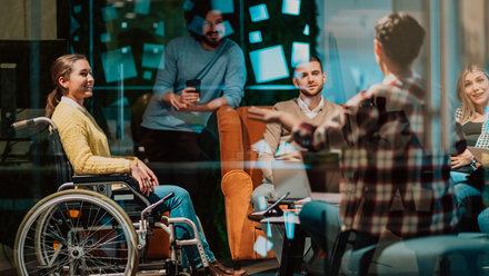 Photo image showing a diverse group of people in the workplace having a conversation and looking engaged.