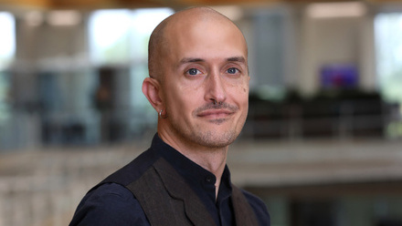 Luke Seraphin, a person with a shaved head and stubble wearing a dark blue shirt and black waistcoat.