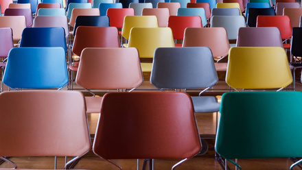 Photo: Multicoloured chairs are lined up in rows about six wide and five deep.