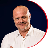 Headshot: Emyr Afan, a man with a short goatee beard and bald head, wearing a white shirt.