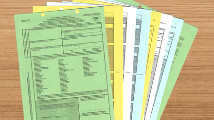 Image showing ATA Carnet forms in multiple colours, fanned out over a wooden desktop.