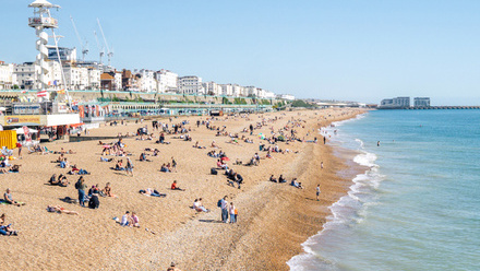 Photo of Brighton beach and skyline on a clear, sunny day. The beach is on the left, sea on the right of the image.