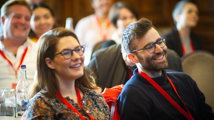 Photo of two attendees - a woman and a man - at Pact Content Without Borders. They are looking off-camera smiling.