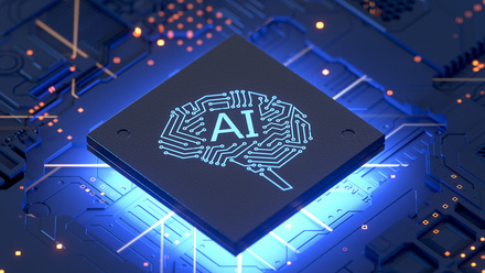 Image of a circuit board lit in blue with a diamond in the middle with the words 'AI' on it and a brain icon.