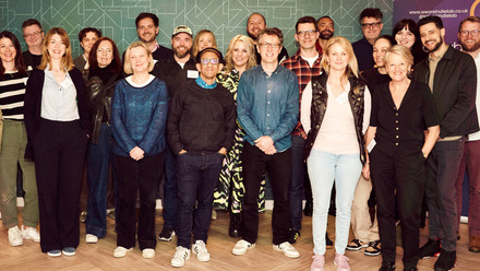 Photo showing a large, diverse group of Indielab participants stood facing the camera and smiling.